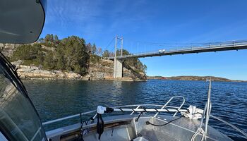 Während der Fahrt zur Tankstelle in Vallersund gleitet das Boot ruhig über das klare Wasser. Die Küstenlinie zieht vorbei und die markante Brücke spannt sich über den Sund – ein typischer Moment auf See in der norwegischen Küstenlandschaft.